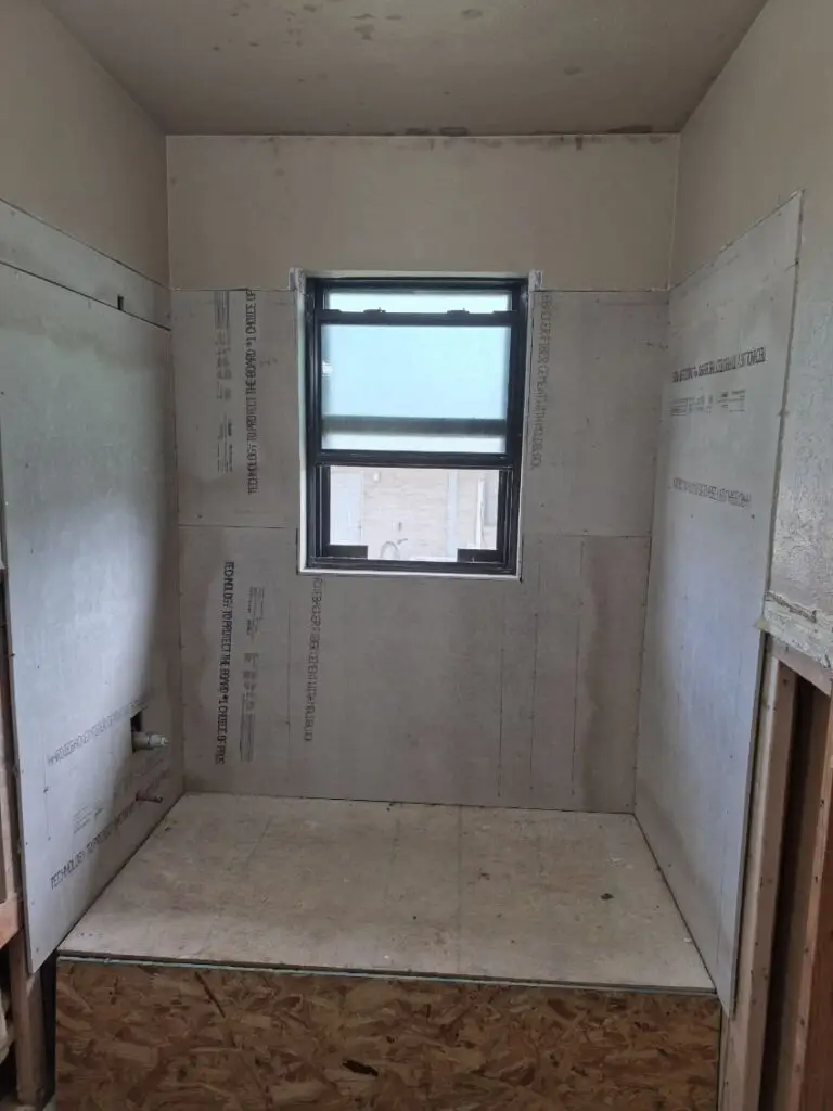 Bathroom shower enclosure with cement board backer installed on all walls, prepped and ready for tile