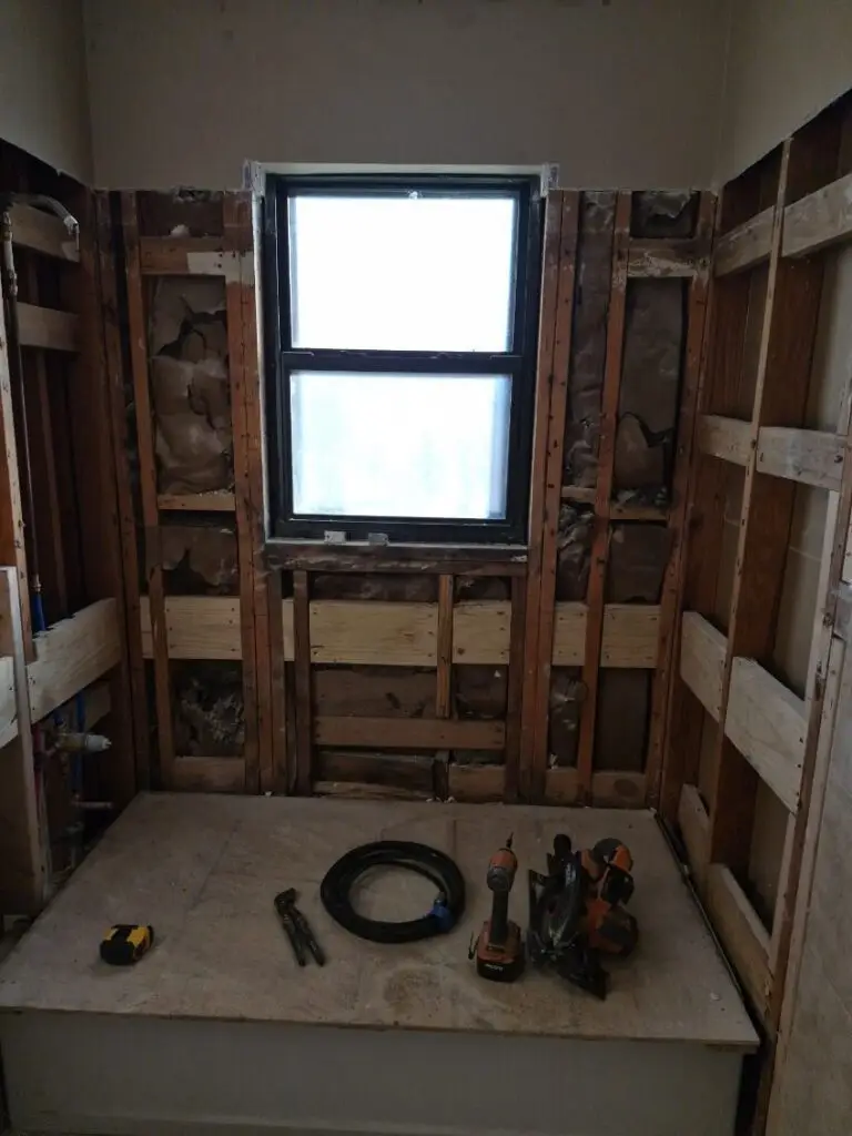Bathroom taken down to the studs during a remodel, with the window opening framed and ready for backer board